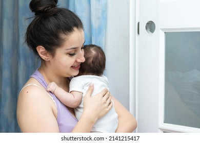 Beautiful Latina Woman Smiling While Holding Her Two Month Old Baby. Mother With Baby In Her Arms Lulling Her To Sleep And Stop Crying. Concept Of Motherhood.