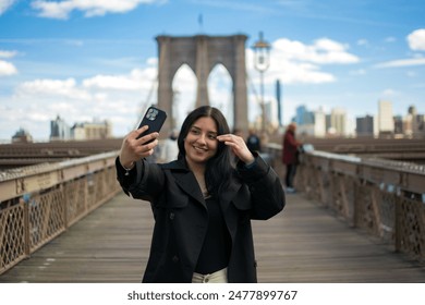 Beautiful latina young girl taking a self photo on the Brooklyn bridge during her trip around the united states, spring season - Powered by Shutterstock