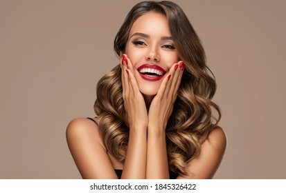 Beautiful Laughing Brunette Model  Girl  With Long Curly  Hair . Smiling  Woman Hairstyle Wavy Curls . Red  Lips And  Nails Manicure .    Fashion , Beauty And Make Up Portrait