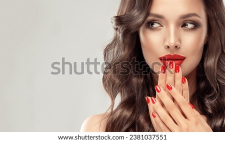 Beautiful laughing brunette model  girl  with long curly  hair . Smiling  woman hairstyle wavy curls . Red  lips and  nails manicure . Fashion , beauty and make up . Expressive facial expressions