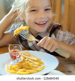 Beautiful Laughing Little Girl Sitting At Table And Eating French Fries From Your Plate.