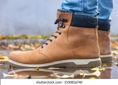 Beautiful leather beige men's high spring-autumn boots. Stylish and fashion casual shoes in autumn weather in the puddle water close-up - Shutterstock ID 1530816740