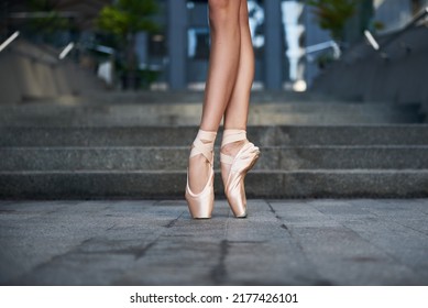 beautiful legs of a ballet dancer in pointe balancing. Pointe shoes close up, Ballerina. Street city photo. grey stairs background  - Powered by Shutterstock