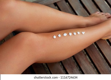 Beautiful Legs  with Sunscreen. Woman Apply Sun Protection Cream on Her Smooth Tanned Legs. Skincare. Sun cream on Feet. Epilation Laser or Shaving Concept.