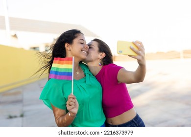 A Beautiful Lesbian Young Couple Embraces And Holds A Rainbow Flag. Girls Taking Selfie Photo