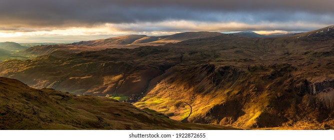 Beautiful light with panoramic view of Western Lake District fells and dramatic dark clouds in the sky.