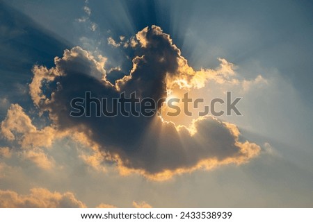 Beautiful light Sun shines behind the cumulus clouds.Colorful sunrise with Clouds over hill.Sun hiding behind a cloud on the day sky.Sunray with dark Clouds sunset.