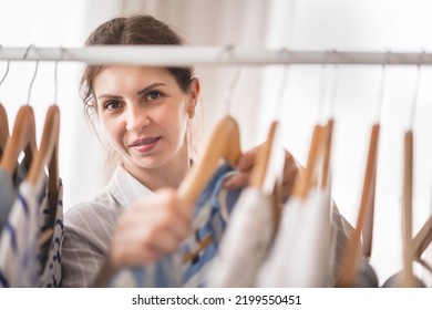 Beautiful Light Wardrobe With Women's Clothing. The Girl Hangs Up And Puts Things In Order In The Closet. Clothes Storage.