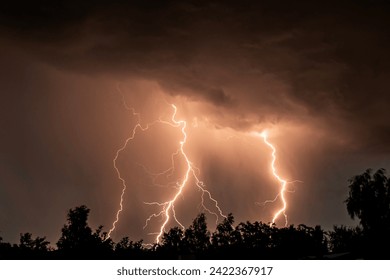 beautiful lightning during a thunderstorm at night in a forest that caused a fire, against a dark sky with rain - Powered by Shutterstock