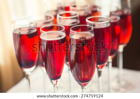 Beautiful line of different colored and red colored alcohol cocktails with smoke on a open air party, tequila, martini, vodka, and others on decorated catering bouquet table on open air party