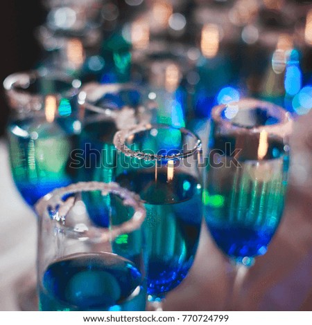 Beautiful line of different coloured cocktails on a Christmas party, tequila, martini, vodka, and others on decorated catering bouquet table 