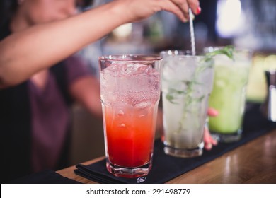 Beautiful line of red and different colored alcohol mojito cocktails with mint on a open air party, tequila, martini, vodka, and others on decorated catering bouquet table on open air event party 
