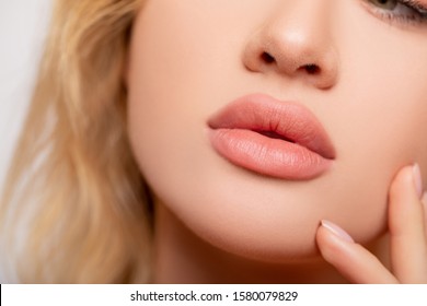 Beautiful lips Close-up. Makeup. Lip matte lipstick. Sexy lips. Part of face, young woman close up. perfect plump lips bodily lipstick.  peach color of lipstick on large lips. Perfect makeup       