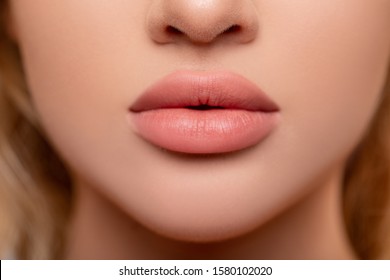 Beautiful lips Close-up. Makeup. Lip matte lipstick. Sexy lips. Part of face, young woman close up. advertisement. perfect plump lips bodily lipstick. peach color of lipstick on large lips.          