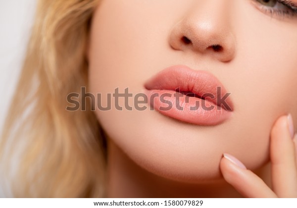 美しい唇の接写 メイクアップ 唇のつや消し口紅 セクシーな唇 顔の一部若い女性の接写 完璧な丸い唇の肉体的な口紅 大きな唇に桃色の口紅 完璧なメイク の写真素材 今すぐ編集