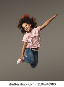 Beautiful little african-american girl jumping a gray studio background, copy space. Studio shot of cute happy child