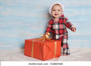 Beautiful Little Baby With Gift Celebrates Christmas. New Year's Holidays. Baby With Christmas Background