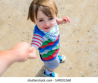 A Beautiful Little Boy Walking And Looking Up At His Parent, Holding Hands