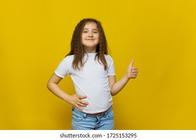 Beautiful little fashion model in white T-shirt on Yelolow studio background. Portrait of cute girl posing in studio - Shutterstock ID 1725153295