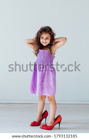 Beautiful little fashionable girl in dress and mom's shoes