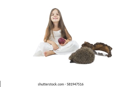 Beautiful little girl with apple in her hand beside hedgehogs