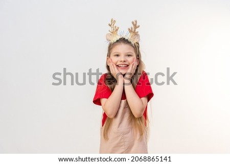 A beautiful little girl in a Christmas outfit is smiling.