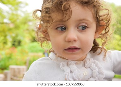 Beautiful Little Girl With Curly Hair Makes A Quizzical Expression, As If She's Just Witnessed A Wipeout