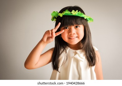 Beautiful little girl doing peace sign wearing shamrock crown in St. Patrick's day
