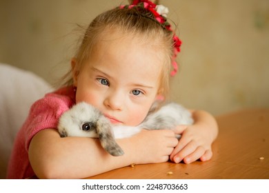 Beautiful little girl with Down syndrome hugs a rabbit - Shutterstock ID 2248703663