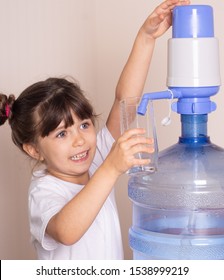 Beautiful Little Girl Drinks Clean Water From A Transparent Glass From Manual Drinking Water Pump At Home. Water Delivery. 