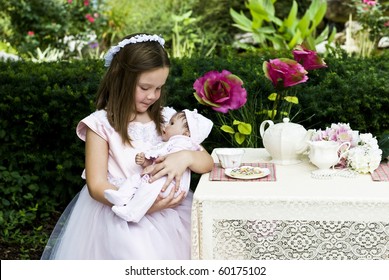 A Beautiful Little Girl Having An Outdoor Tea Party With Her Baby Doll