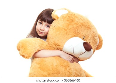 beautiful little girl holding a big teddy bear, isolated on white