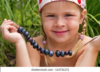 Beautiful little girl holding freshly picked blueberries on straw