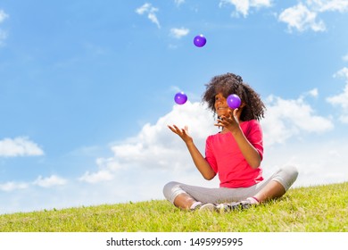 Beautiful little girl juggle with balls on lawn