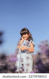 A beautiful little girl in a lavender field against a blue sky. Vertical image.