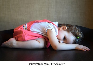 A Beautiful Little Girl Lies In Fetal Position And Peeps. Soft Focus.