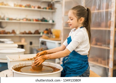 beautiful little girl making a pot of clay in a pottery workshop