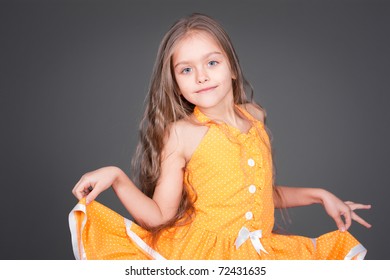 Beautiful Little Girl In Orange Dress At The Studio On Gray