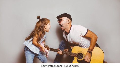 Beautiful Little Girl Playing Guitar With Her Father. Funny Lifestyle Picture. Happy Family Timespending. Girl Holding Pink Ukulele Ang Singing And Jumping,