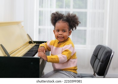 Beautiful Little Girl Playing Piano In The Living Room At Home Or Concept Music School. Preschoolers Enjoy Learning To Play Music And Art. Educational Skills For Children