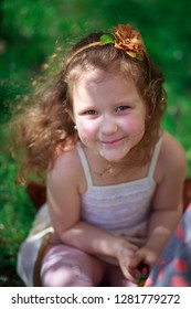 Beautiful Little Girl Sitting On Grass And Looking Up. Happy Baby On Walk. No Mobile Phone And Other Gadgets.