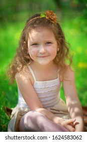 Beautiful Little Girl Sitting On Grass And Looking Up. Happy Baby On Walk. No Mobile Phone And Other Gadgets. Spring And Flowering Of Spring Flowers Without Allergies