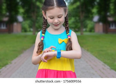 Beautiful Little Girl With A Smile On Her Face Is Using Smart Watch On The Street.Safety Concept