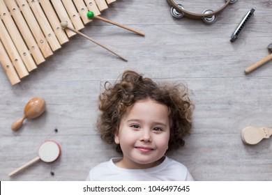 beautiful little girl surrounded by several percussion instruments on a wooden grey table