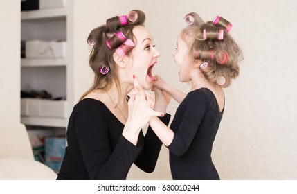 Beautiful Little Girl And Woman, Has Crying Fun Face, Long Hair, Curlers Roller, Black Underwear Combies Dress. Family Portrait. Creative Concept. Close Up. Mom And Daughter, Relationship Love