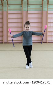 Beautiful little gymnast girl, performing art gymnastics element with mace in fitness class. Sport, training, stretching, active lifestyle concept