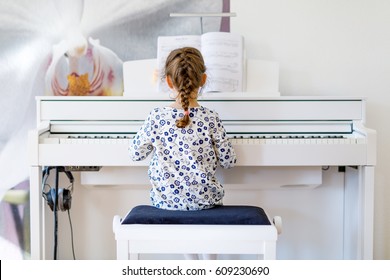 Beautiful Little Kid Girl Playing Piano In Living Room Or Music School. Preschool Child Having Fun With Learning To Play Music Instrument. Education, Skills Concept.