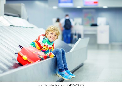 Beautiful Little Tired Kid Boy At The Airport, Traveling. Happy Child Waiting With Kids Suitcase On Baggage Carousel. Canceled Flight Due To Pilot Strike.