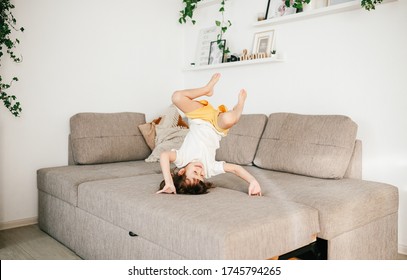 Beautiful Little Toddler Tumbling On Sofa At Home. Child Learn To Tumble. Tumbling Tutorial. Gymnastics At Home, Tricks