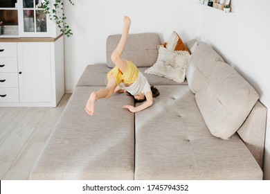 Beautiful Little Toddler Tumbling On Sofa At Home. Child Learn To Tumble. Tumbling Tutorial. Gymnastics At Home, Tricks